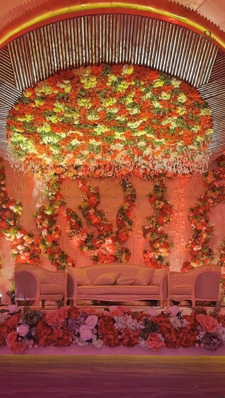 Royal floral stage setup with orange marigold wall by Revaah Decor